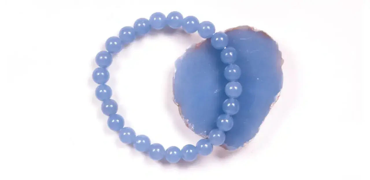 Armband aus hellblauen Perlen, die auf einem Stück Angelit Stein liegen.