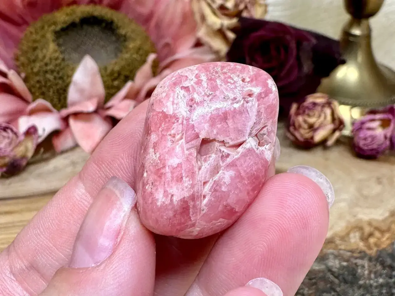 Ein pinker Rhodochrosit-Stein in einer Hand. Die Rhodochrosit Wirkung soll Liebe und Heilung f&ouml;rdern.