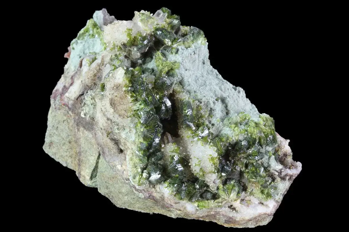 Ein faszinierender Epidot Stein mit leuchtend gr&uuml;nen Kristallen, die aus einem hellgrauen Gestein wachsen.