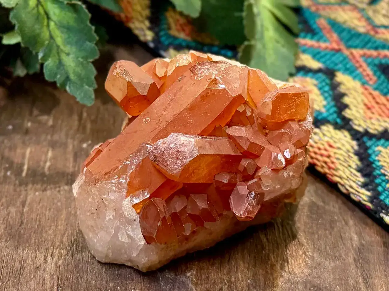 Ein Cluster aus leuchtend orangefarbenen Quarzspitzen, die auf einem Holzuntergrund liegen. Was ist Quarz? Ein faszinierendes Mineral!