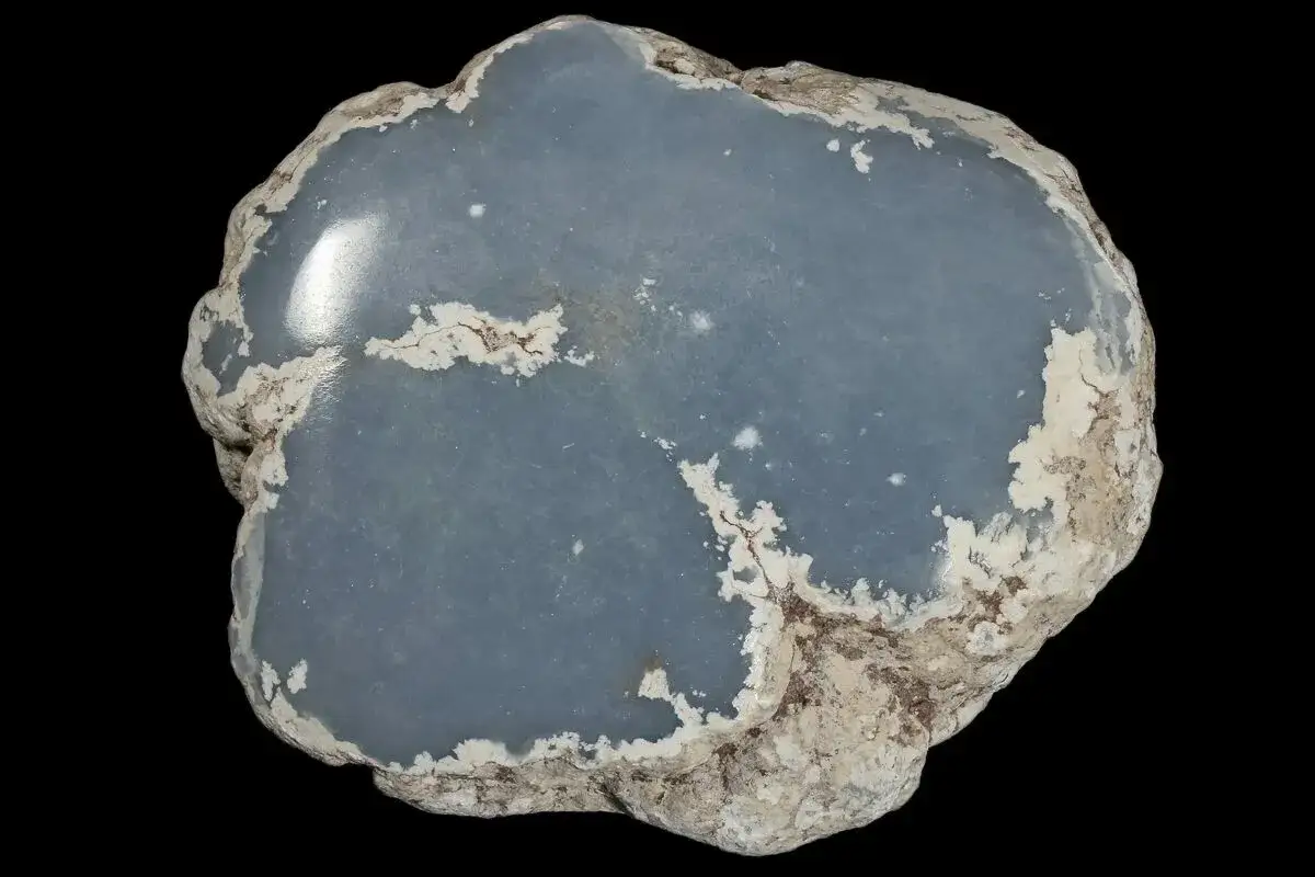 Ein glatter, blauer Angelit Stein mit rauer, wei&szlig;er Kruste.
