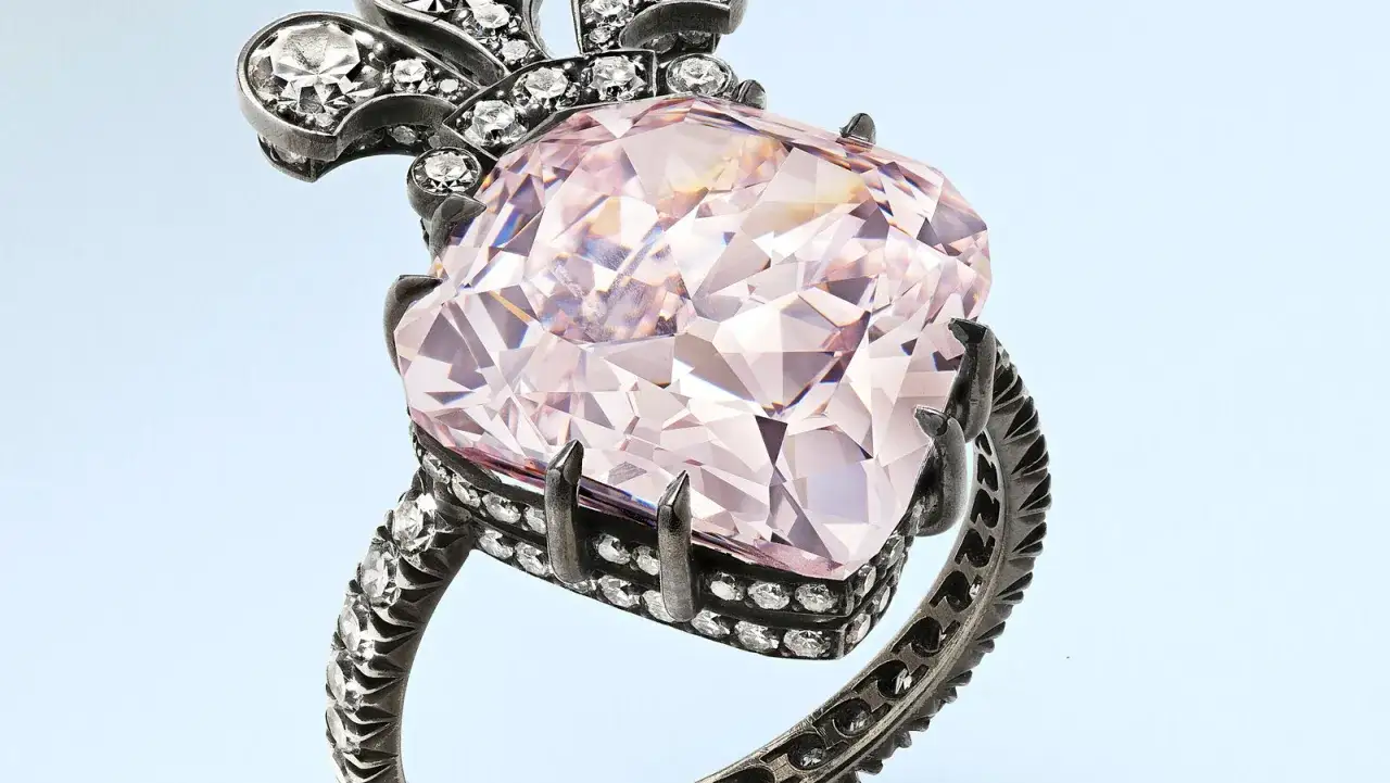 Ein Ring mit einem großen, rosafarbenen Diamanten, der zeigt, welche Diamanten Farbe ist die teuerste. Kleine weiße Diamanten zieren die Fassung.