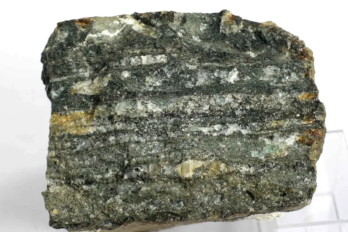 Gestreifter Gesteinsbrocken mit glitzernden Einschlüssen, der an Katzengold erinnert.
