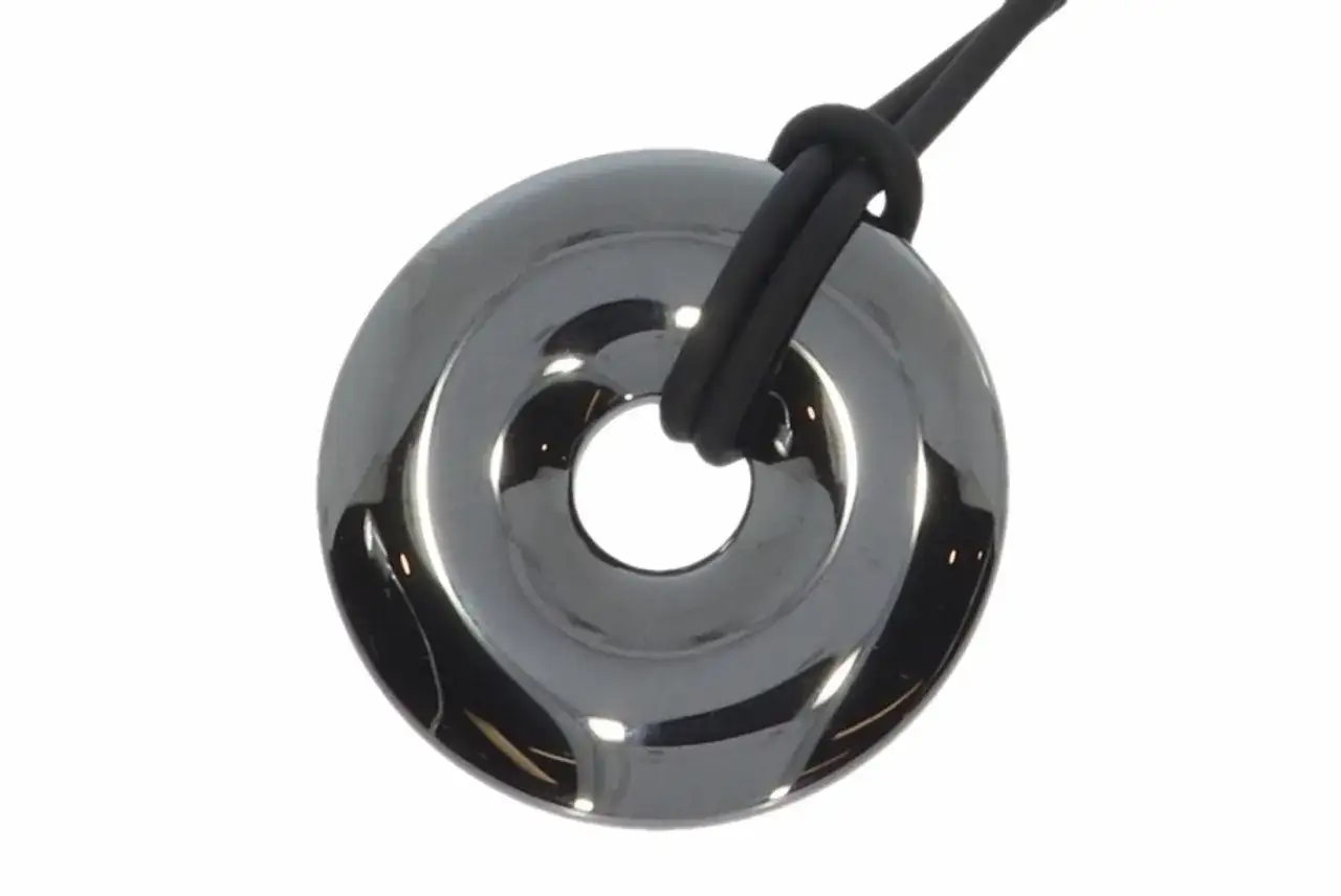 Gl&auml;nzender H&auml;matit-Anh&auml;nger in Ringform, der an einem schwarzen Band befestigt ist. Trotz seiner Sch&ouml;nheit ist H&auml;matit nicht giftig.