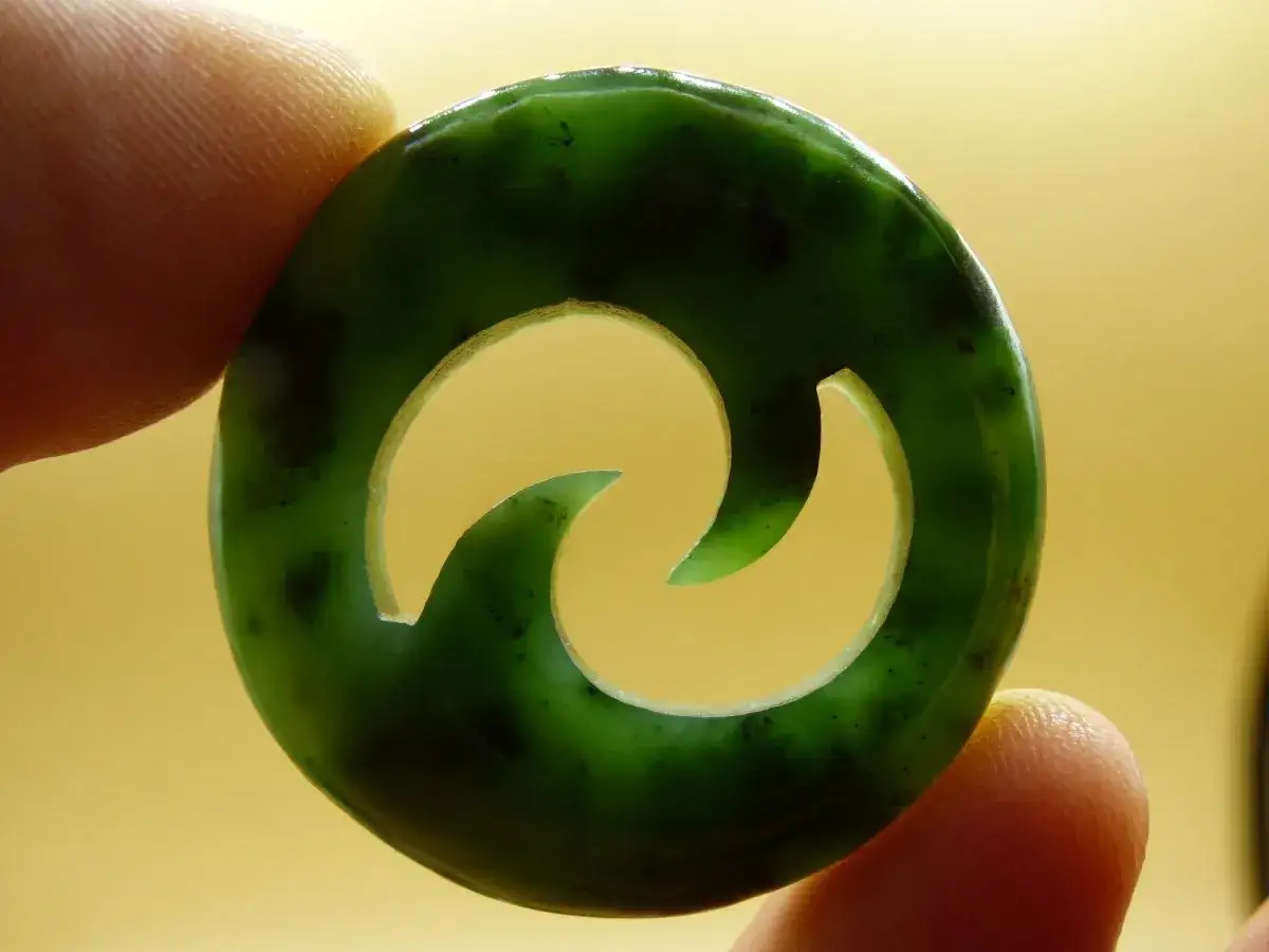 Grüner Jadeanhänger mit Spiralmuster, der die Bedeutung von Harmonie und Fluss symbolisiert.