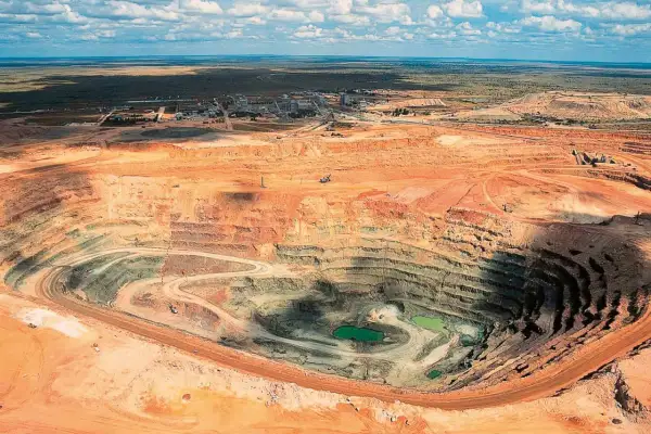 Tiefer Krater einer Mine, wo der **diamanten abbau** stattfindet. Grüne Wasseransammlungen am Grund.