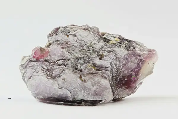 Ein schuppiger, lila-grauer Lepidolith-Stein mit glänzenden Oberflächen und einem kleinen, rosa Kristall.