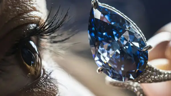Ein Auge blickt auf einen funkelnden blauen Diamanten, dessen Wert unermesslich ist.
