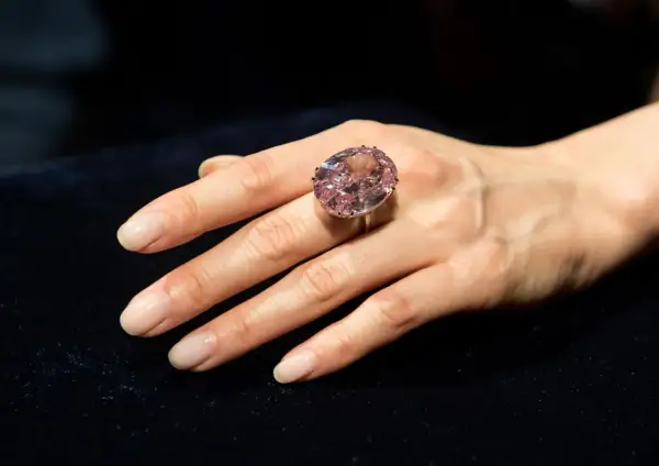 Ein großer, ovaler rosa Diamantring, der den teuersten Diamant der Welt Preis repräsentiert, wird an einer Hand getragen.