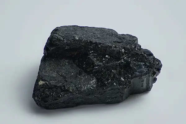 Ein glänzender, schwarzer Stein, der an einen Brocken Onyx erinnert, liegt auf weißem Grund.