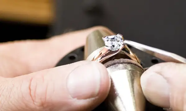 Ein Juwelier setzt einen funkelnden Diamanten, einen kostbaren Edelstein, in eine Ringschiene ein.
