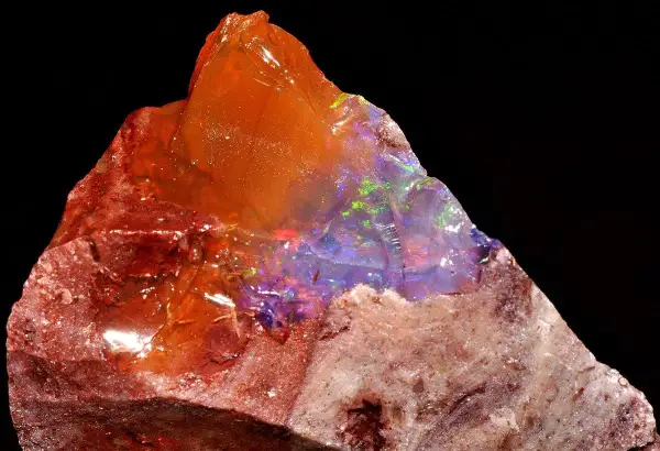 Ein roher Feueropal mit leuchtenden Farben, dessen feurige Wirkung durch das Spiel von Licht und Farbe im Stein fasziniert.