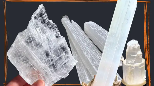 Mehrere transparente, säulenförmige Kristalle, die wie Eis aussehen. Ein großer, flacher Selenit Stein wird von einer Hand gehalten.