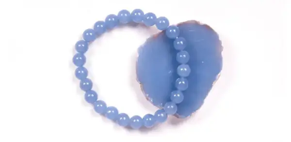 Armband aus hellblauen Perlen, die auf einem Stück Angelit Stein liegen.